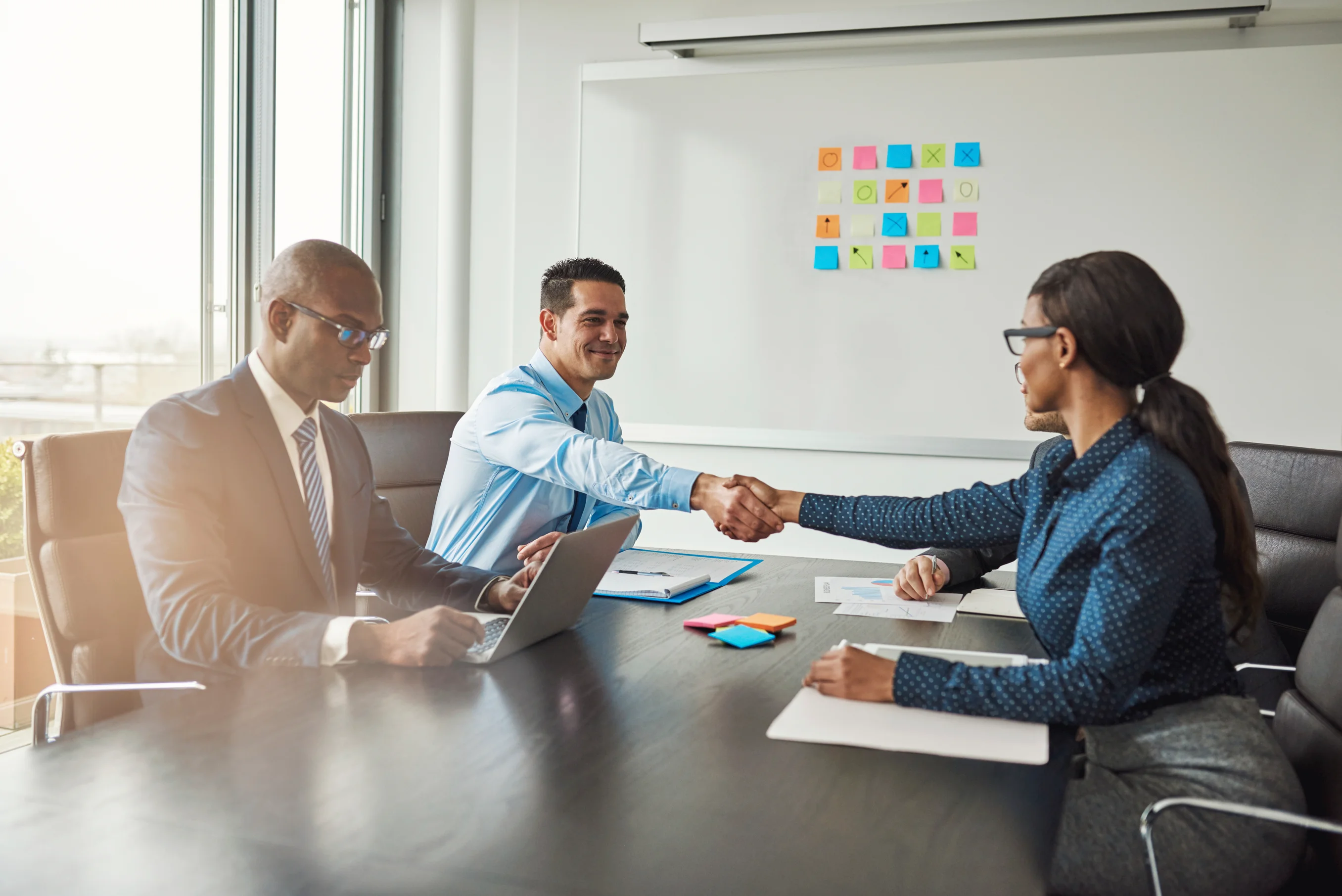 Two businesspeople shaking hands across a meeting table