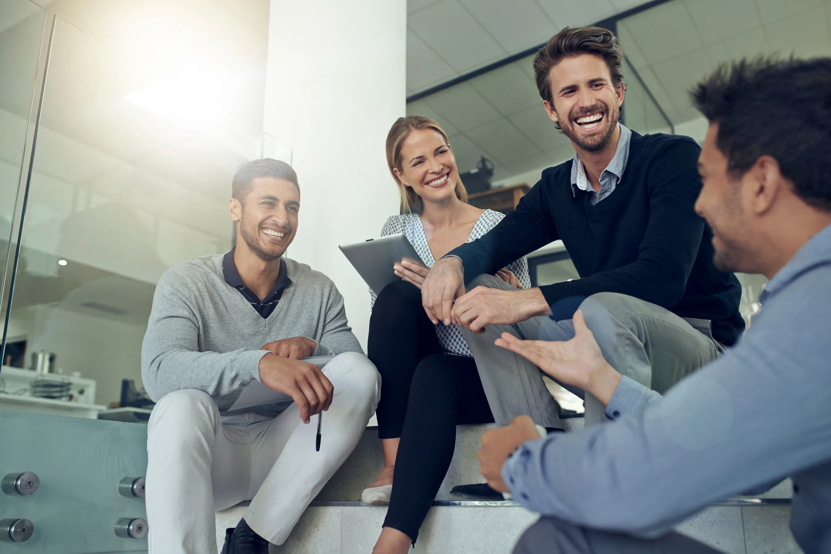 Colleagues sitting on office steps, smiling and talking together